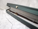 The Raymond Weil watch resting in a dark green presentation box, open to display the watch and strap on a white liner.