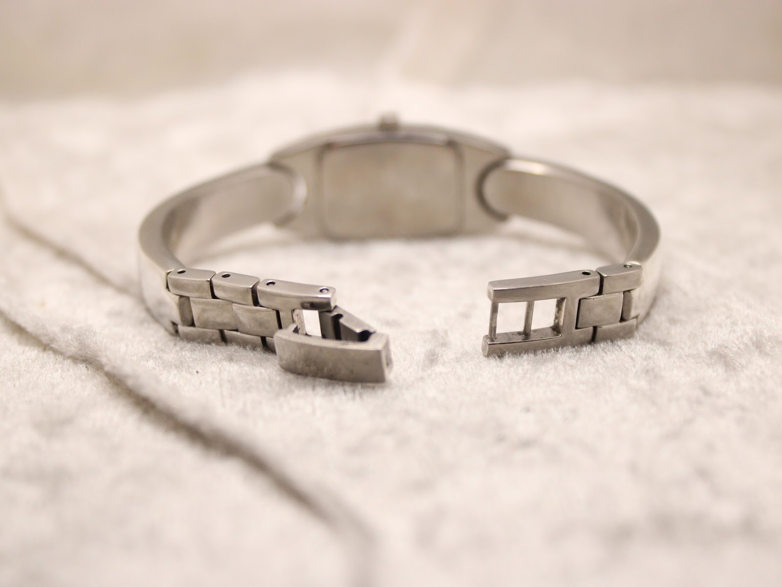 Rear view of the open folding clasp on the stainless steel bangle bracelet of the Tissot watch.