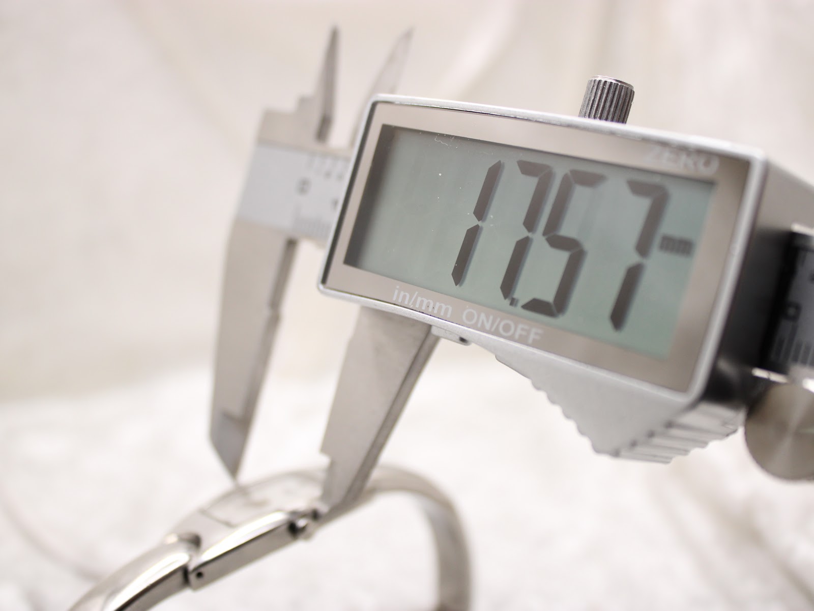 Digital caliper measuring the Tissot watch case, displaying a precise diameter of 17.57 mm.