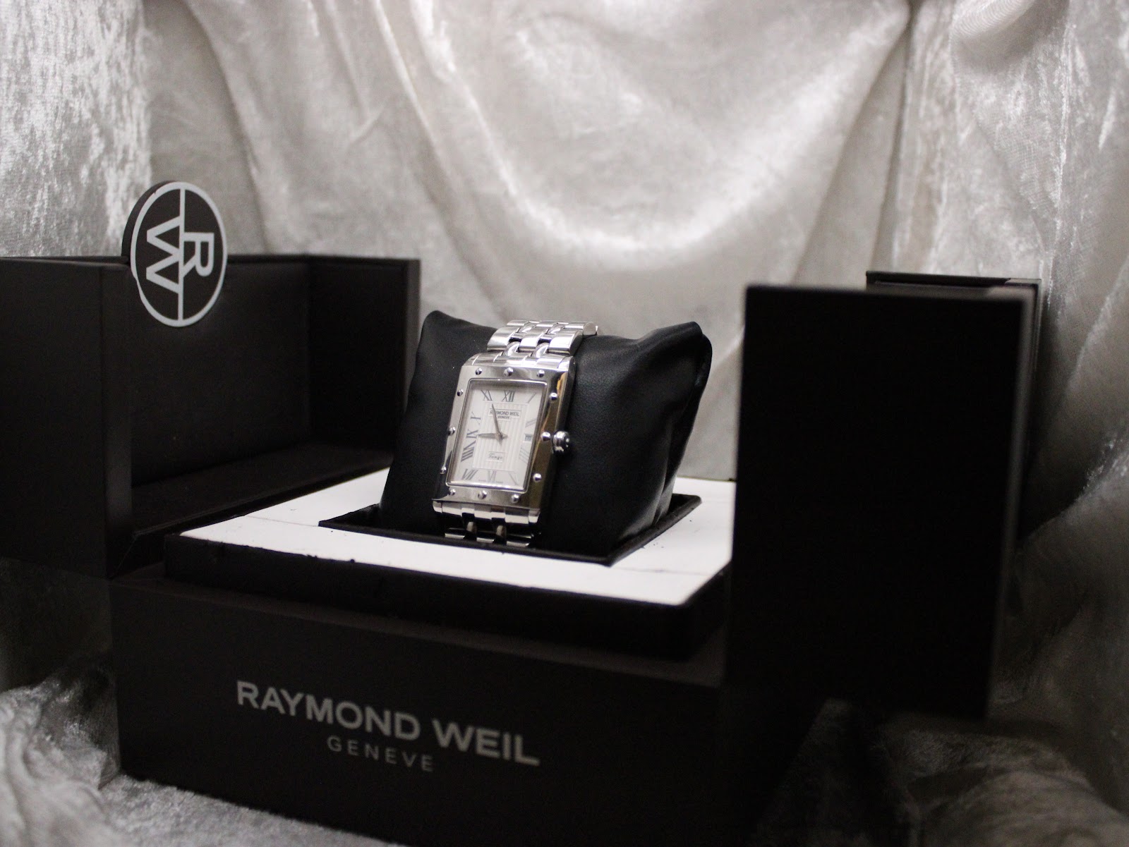 Raymond Weil Tango watch displayed in its original black presentation box with an 'RW' logo detail.