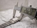 Digital caliper measuring the watch case diameter at 28.28mm, with the watch resting on a support.