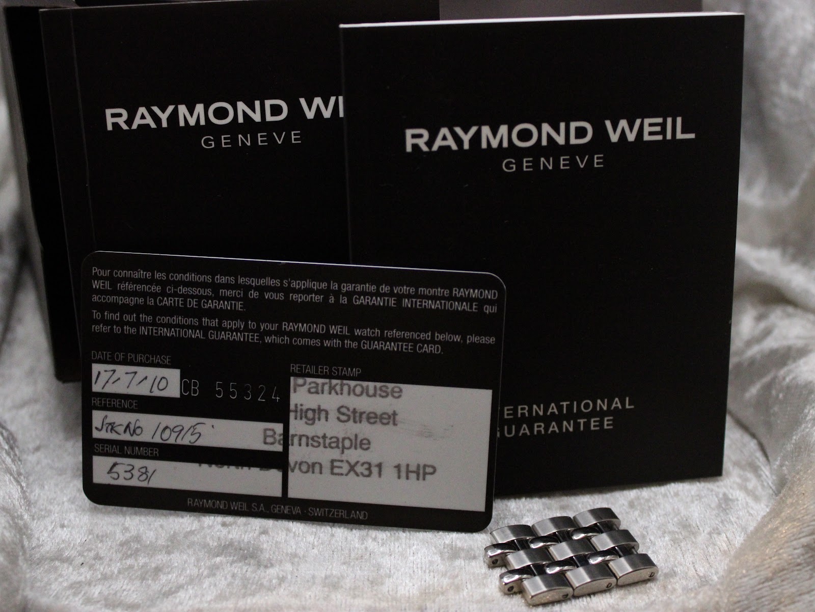 Original Raymond Weil warranty card, instruction booklets, and additional stainless steel bracelet links.