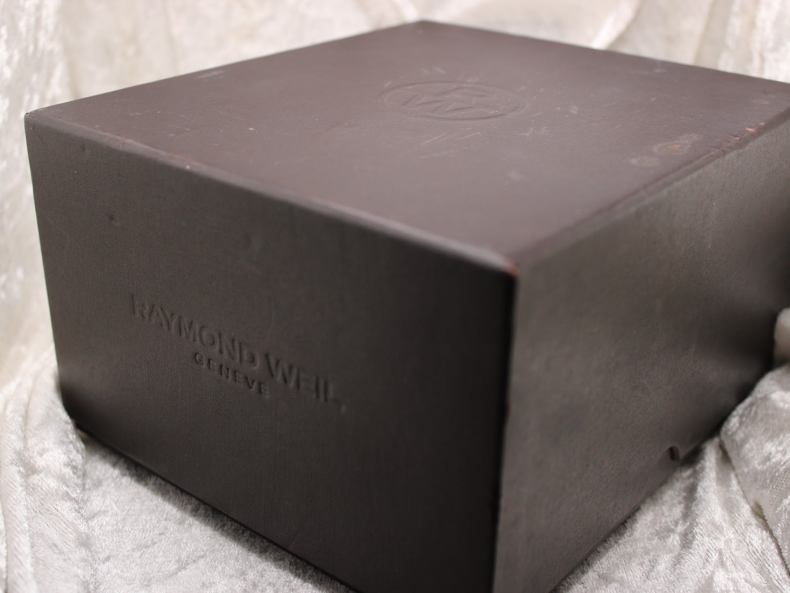 Outer brown Raymond Weil presentation box with an embossed 'Raymond Weil Genève' logo.