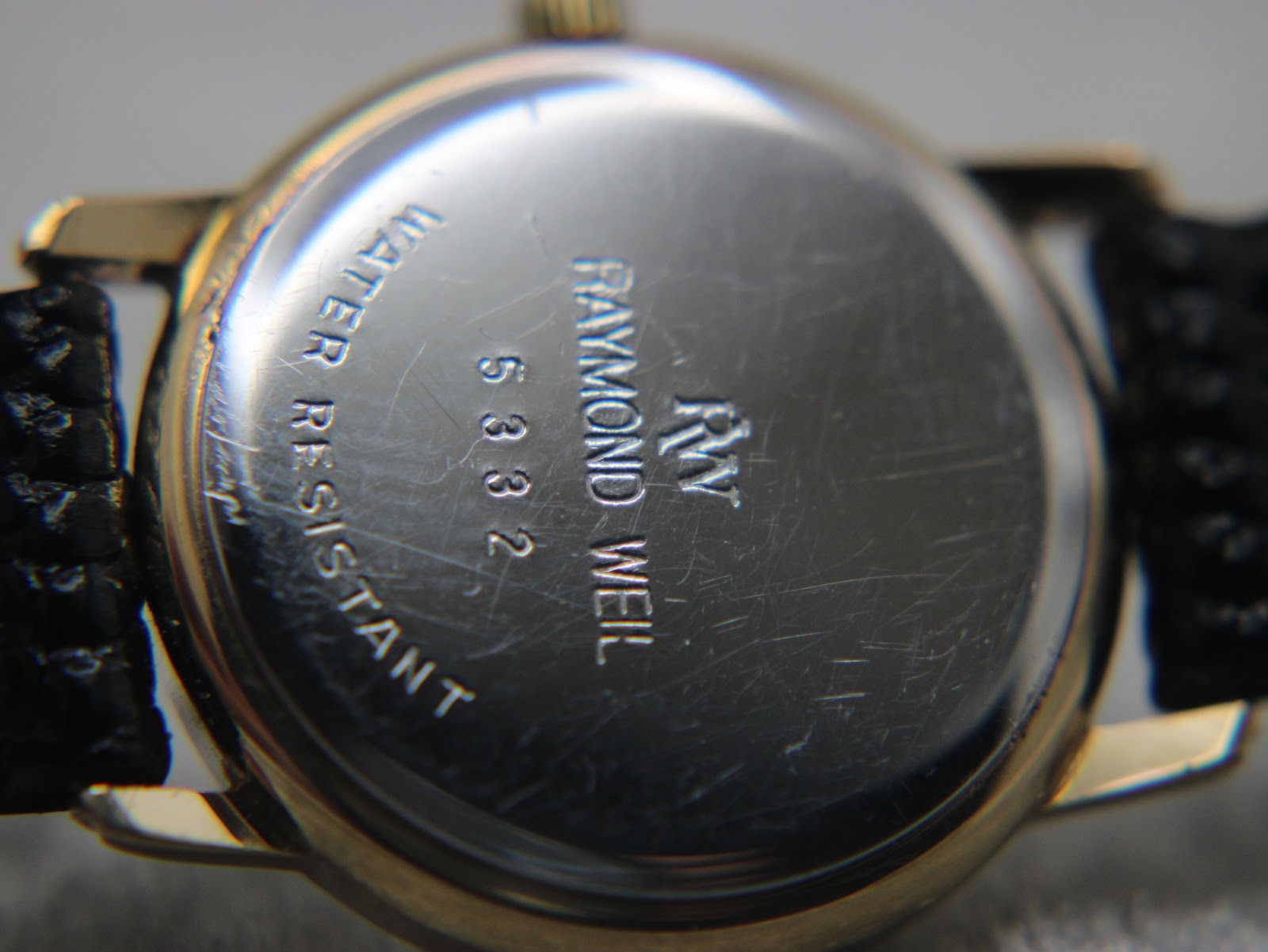 Close-up of the polished case back, showing 'RAYMOND WEIL', '5332', and 'WATER RESISTANT' engravings with some light scratches.