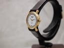 Angled side view of the Raymond Weil watch, showing the gold-tone case, crown, and texture of the brown leather strap.