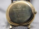 Close-up of the watch's case back, engraved with 'Raymond Weil', '18K Gold Electroplated', 'Swiss', and model '9920'.