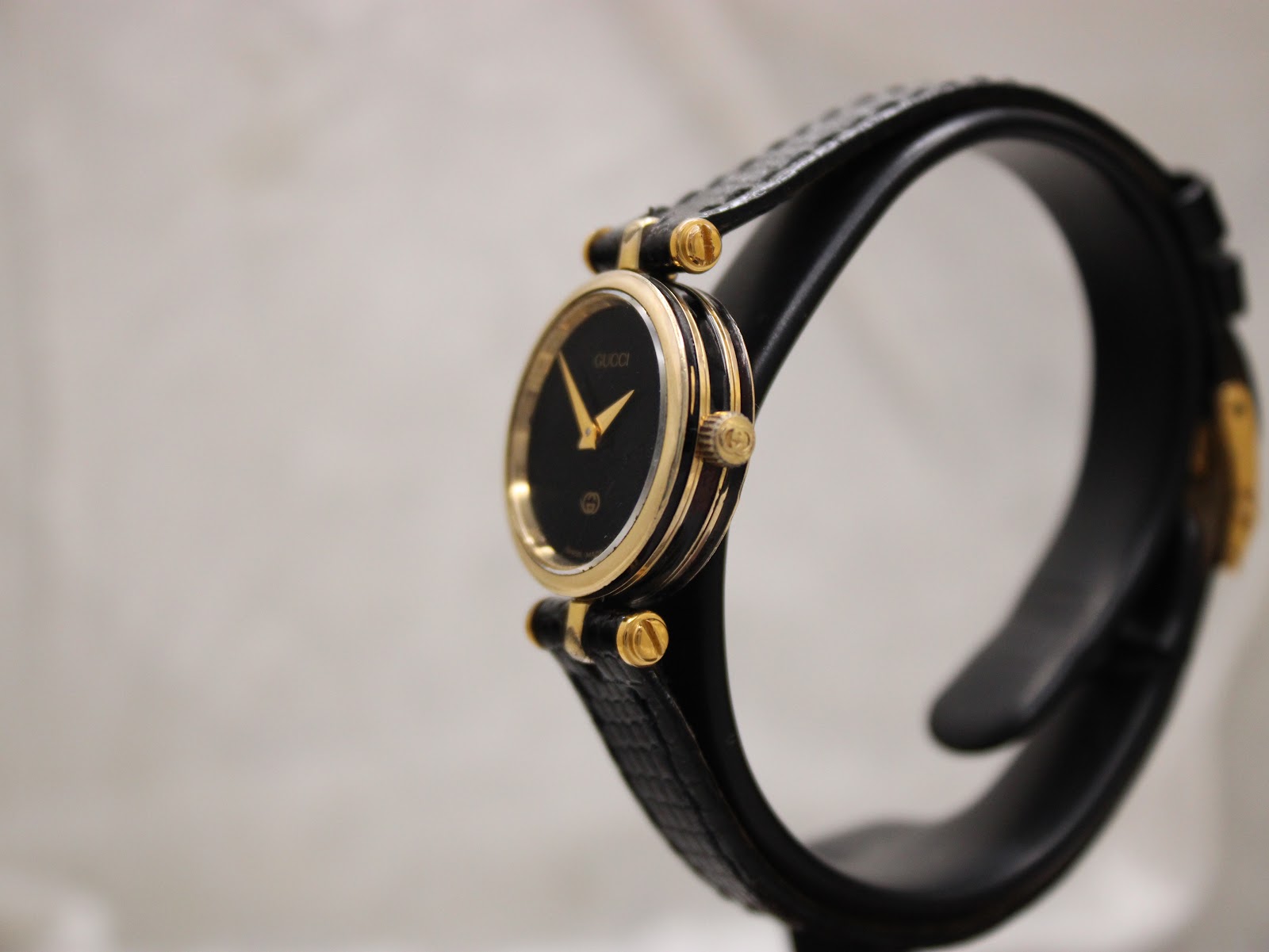 Angled side view of the Gucci 2000L watch, highlighting the ridged gold-plated case and crown details.