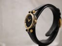 Angled side view of the Gucci 2000L watch, highlighting the ridged gold-plated case and crown details.