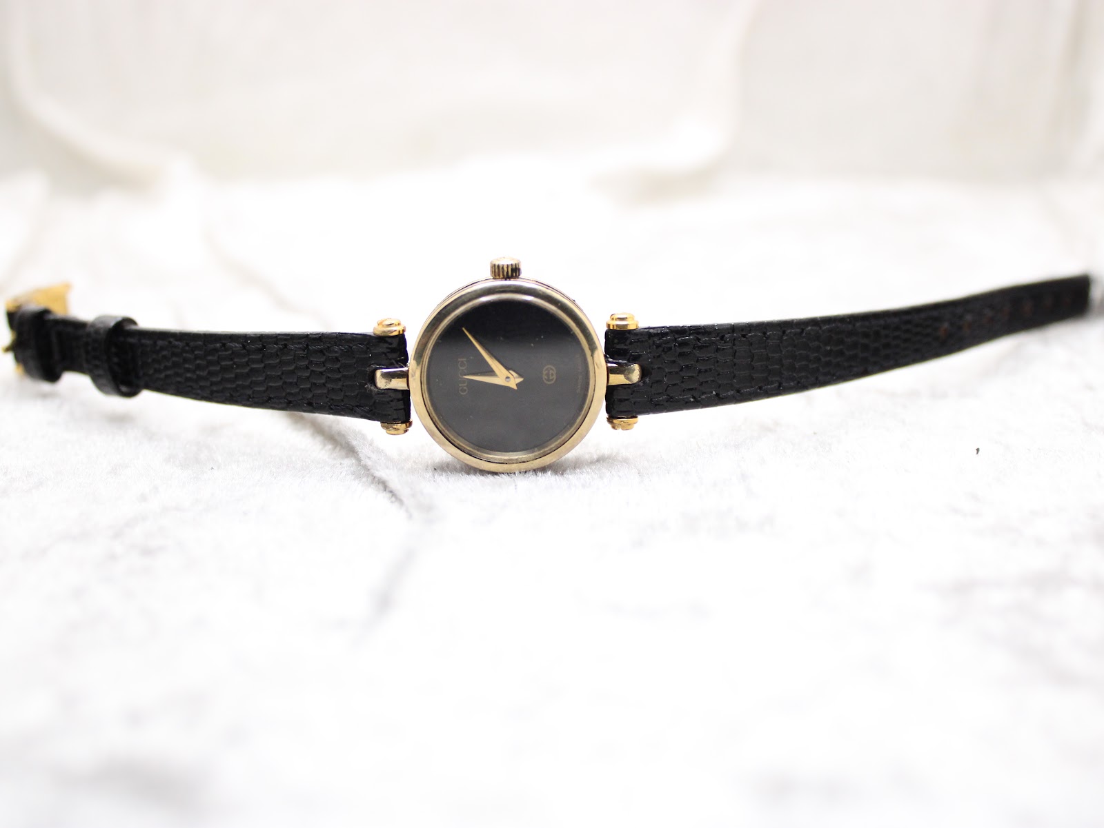 Full length view of the Gucci 2000L watch with its black lizard calf strap on a light background.