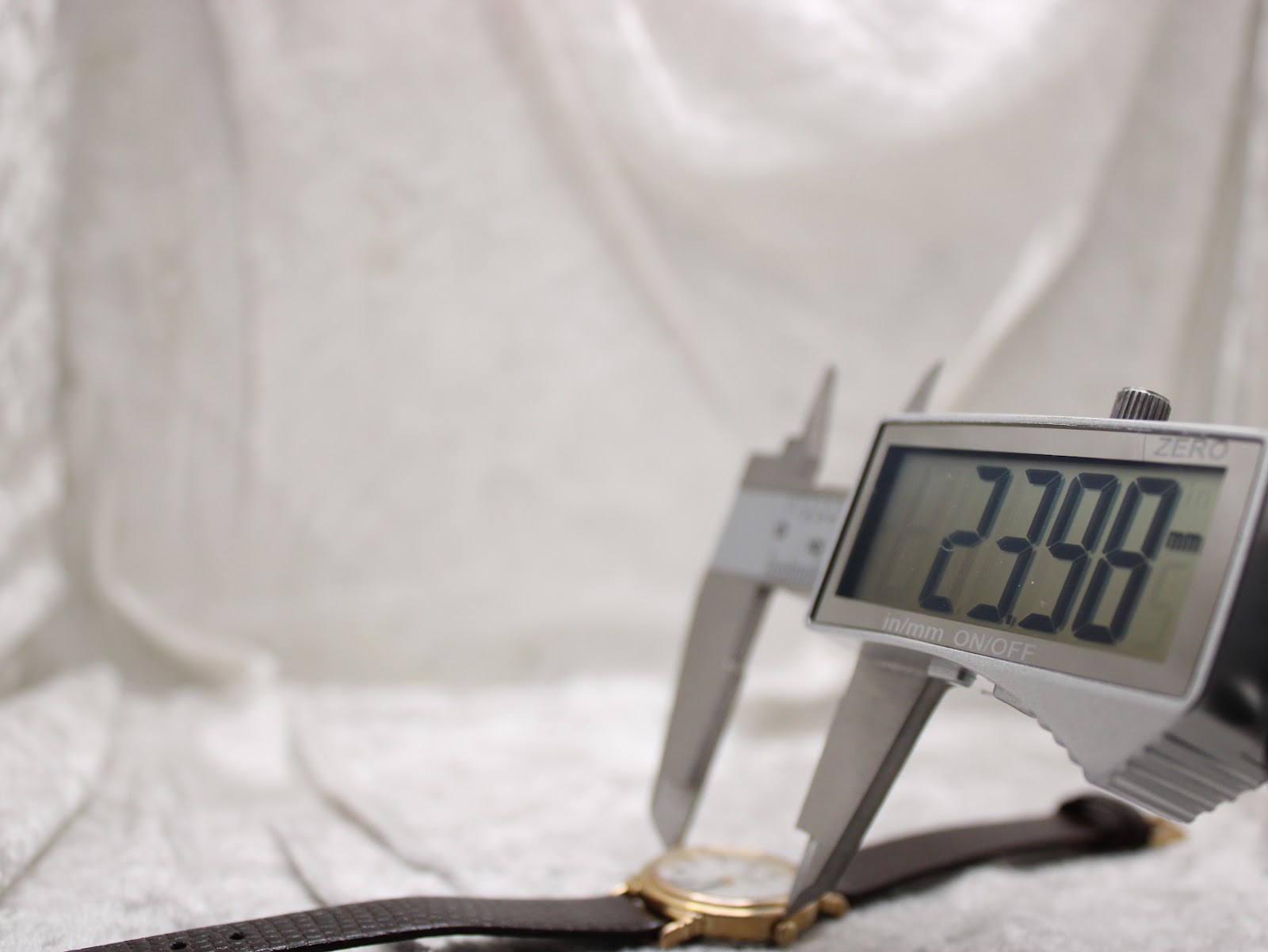 Close-up showing a digital caliper measuring the Raymond Weil 5331 case diameter at 23.98mm.