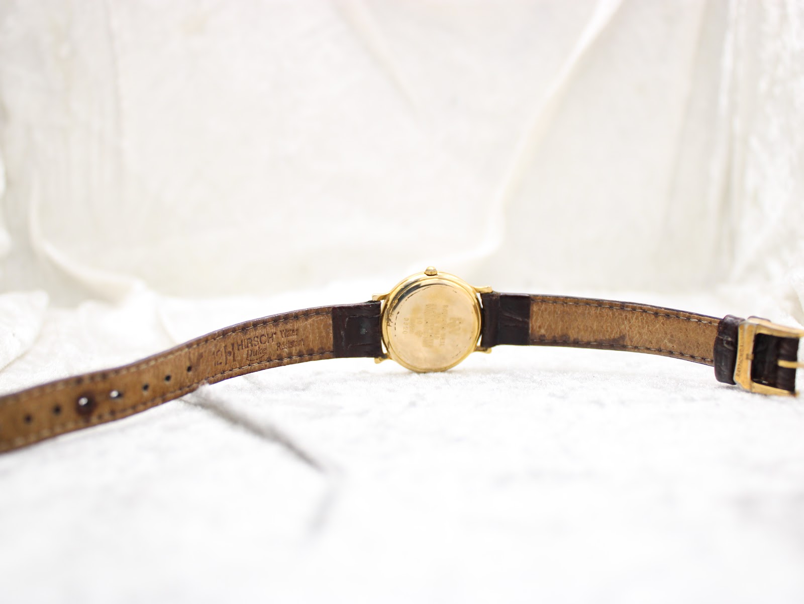 Full back view of the Raymond Weil watch showing the case back and the inside of the black leather Hirsch strap with its markings.