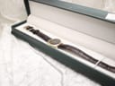 The Raymond Weil watch and strap presented in a dark green display box on a white textured background.