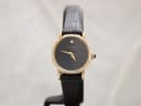 Front view of gold-tone Raymond Weil Geneve watch with black dial, gold hands, and a single diamond marker at 12 o'clock.