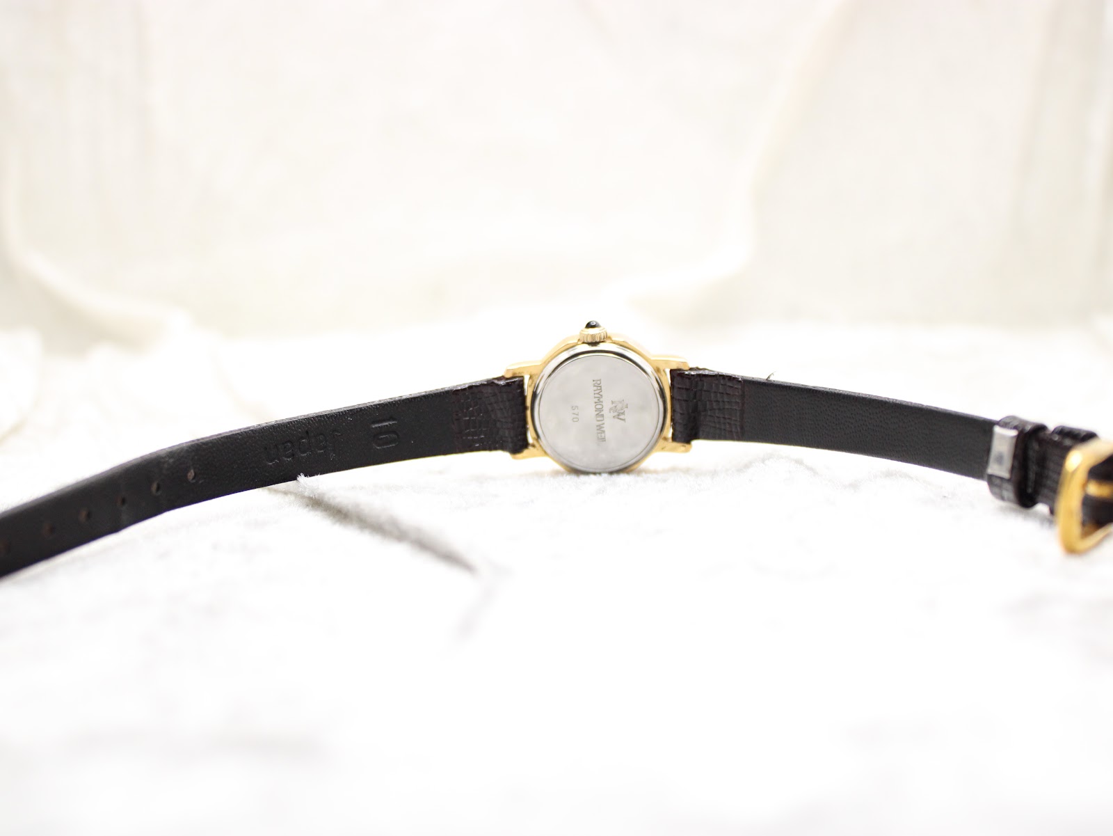 Full length rear view of the Raymond Weil Geneve watch, showing the case back and the full extent of the black leather strap.