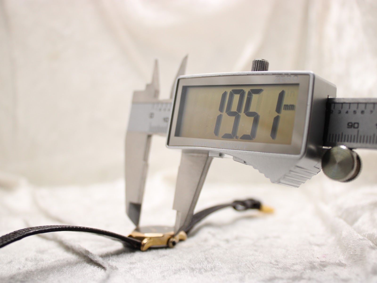 Close-up of a digital caliper measuring the case diameter of the watch, showing a reading of 19.51mm.