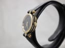 Side profile of the Gucci 2000L watch on a display stand, showcasing its slim fluted gold-plated case and crown.