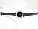 Overhead view of the entire Gucci 2000L watch, displaying the long black leather strap and the round gold-plated case.