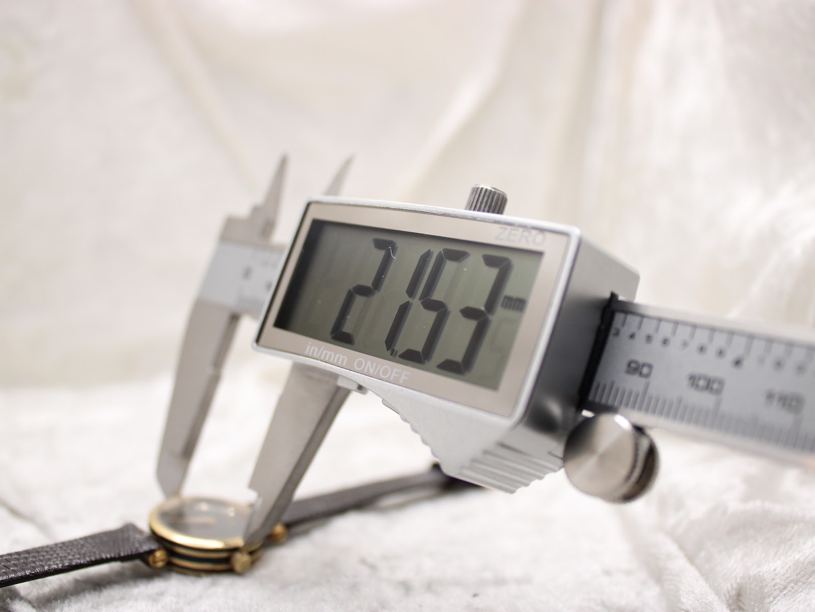 A digital caliper measuring the watch case diameter, displaying a precise reading of 21.53mm on the screen.