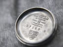 Interior view of the watch case back, showing markings like "20 MICRONS", "SWISS MADE", "17150", and the Tissot logo.