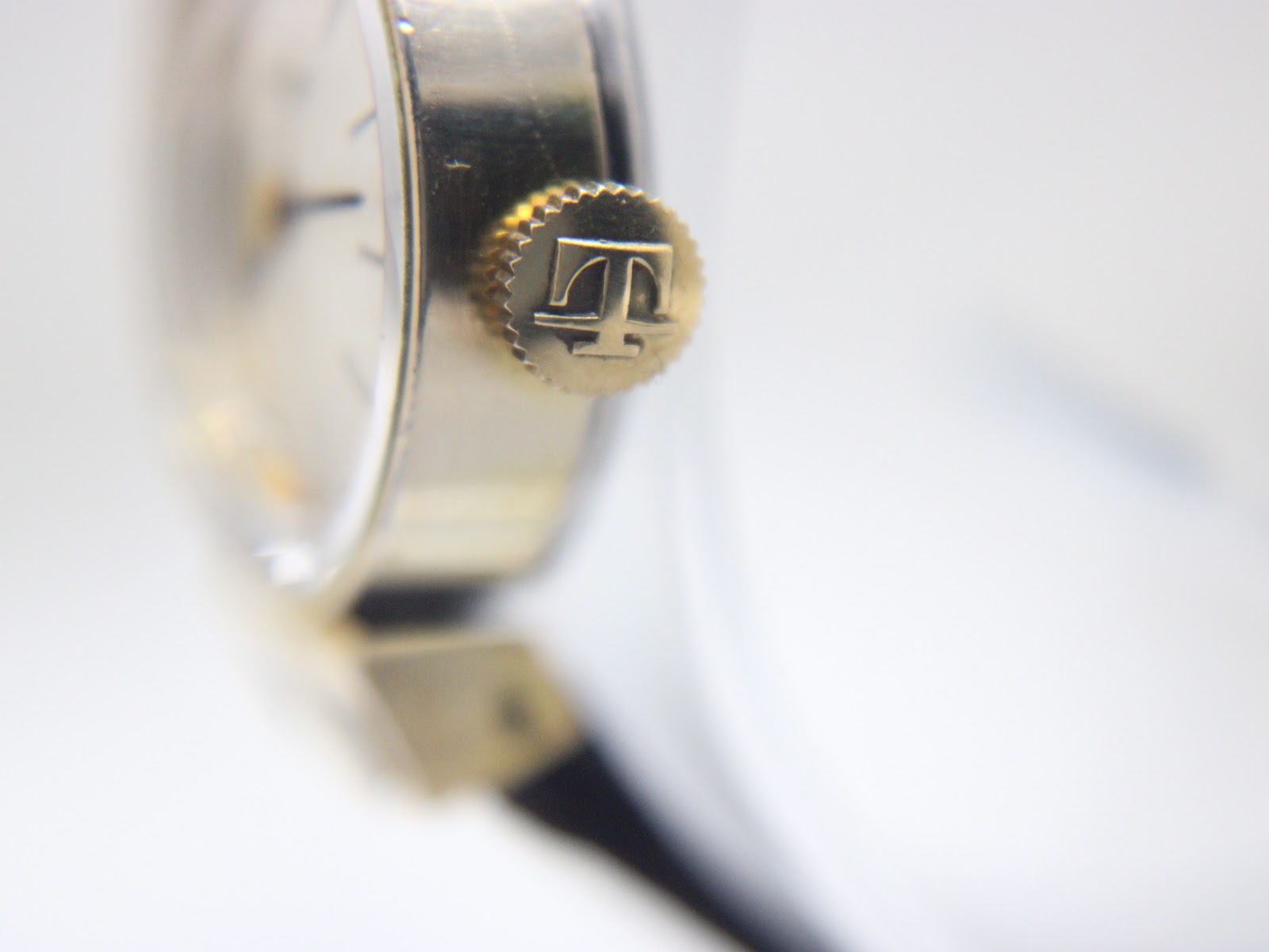 Extreme close-up of the textured gold crown, distinctly featuring the Tissot 'T' emblem.