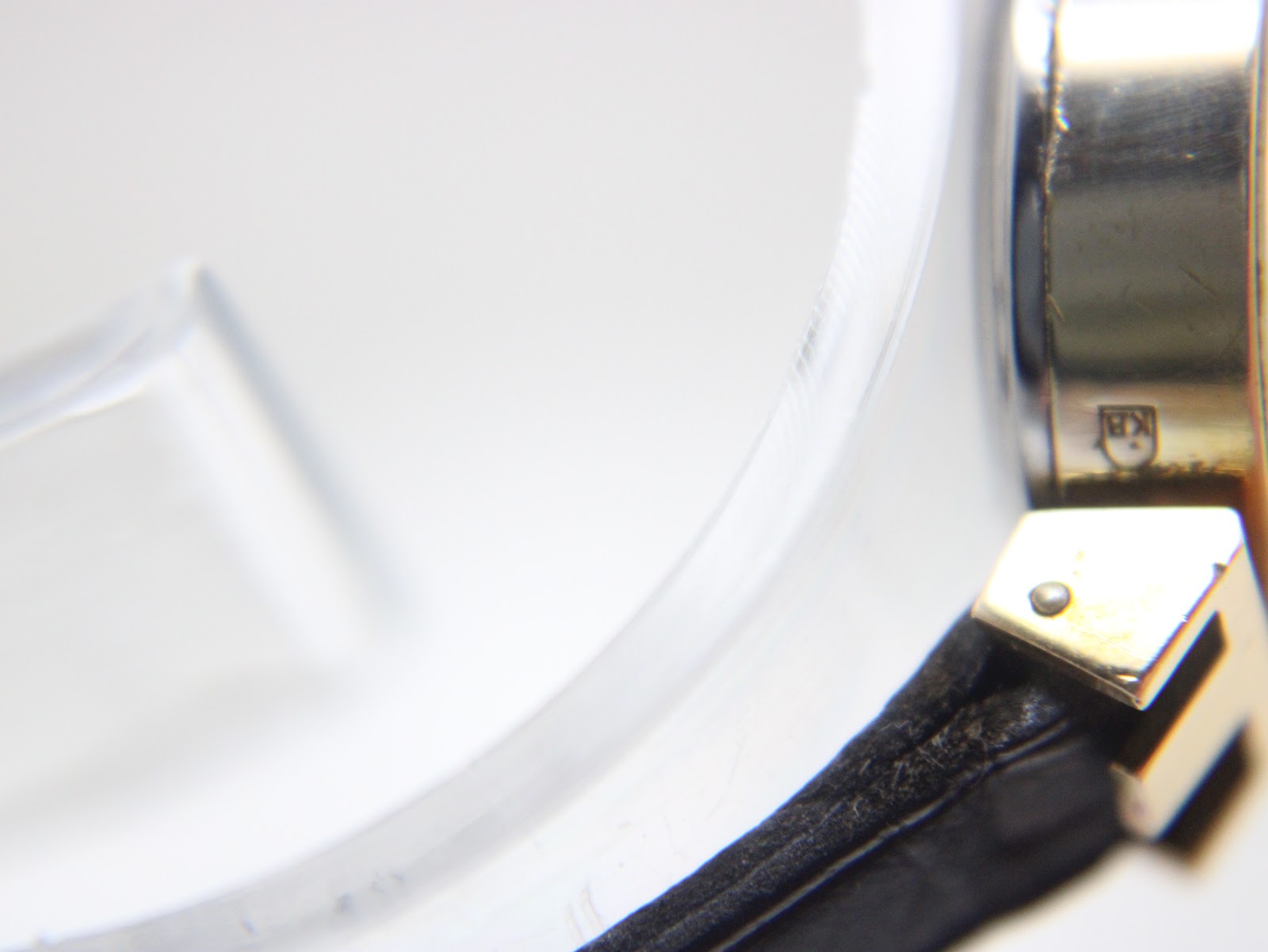 Detail shot of the case side where the strap attaches, showing the "KB" hallmark and "20" micron plating detail.