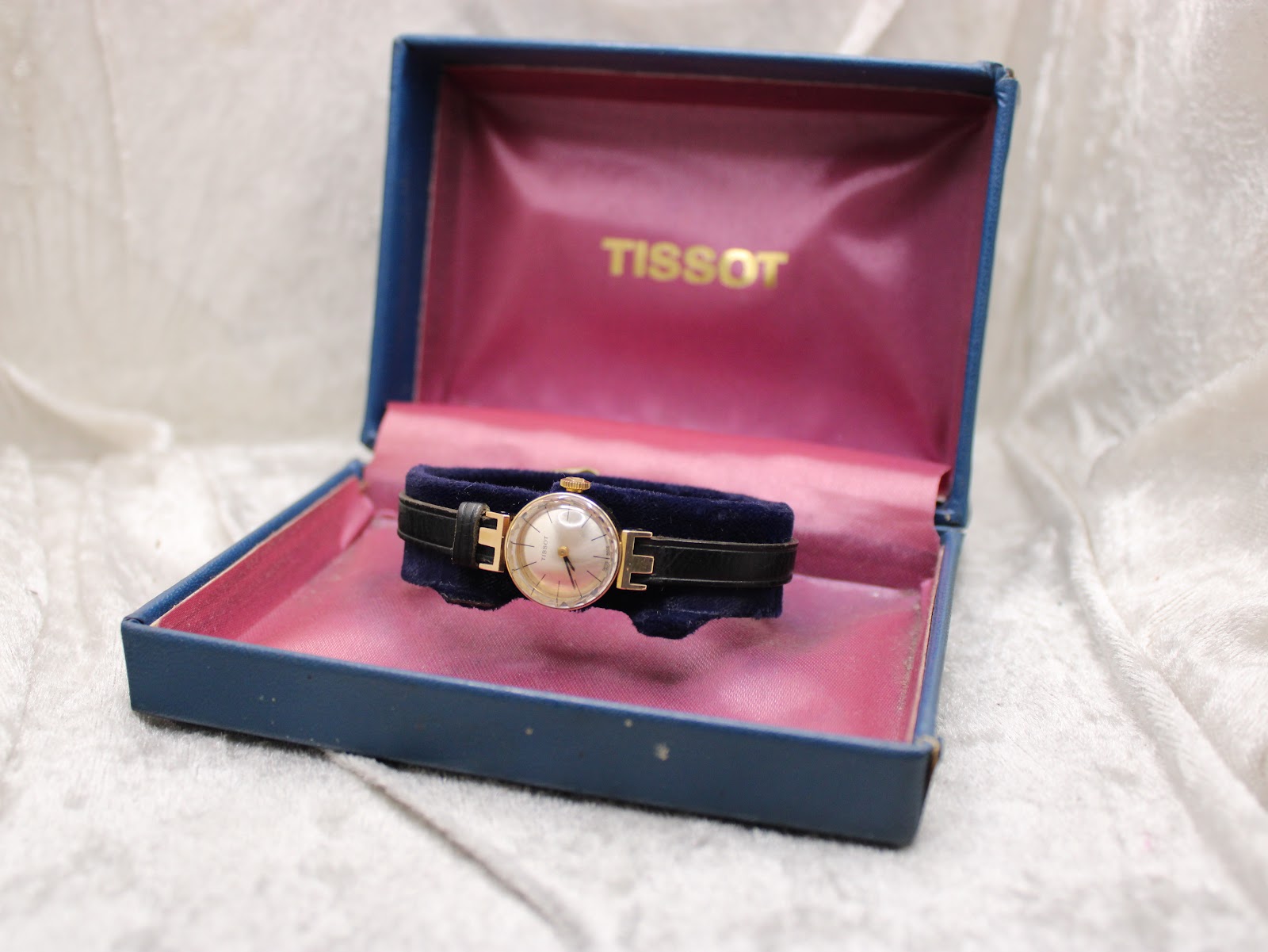 The Tissot 17150 watch resting inside its original blue Tissot presentation box with a pink velvet interior.