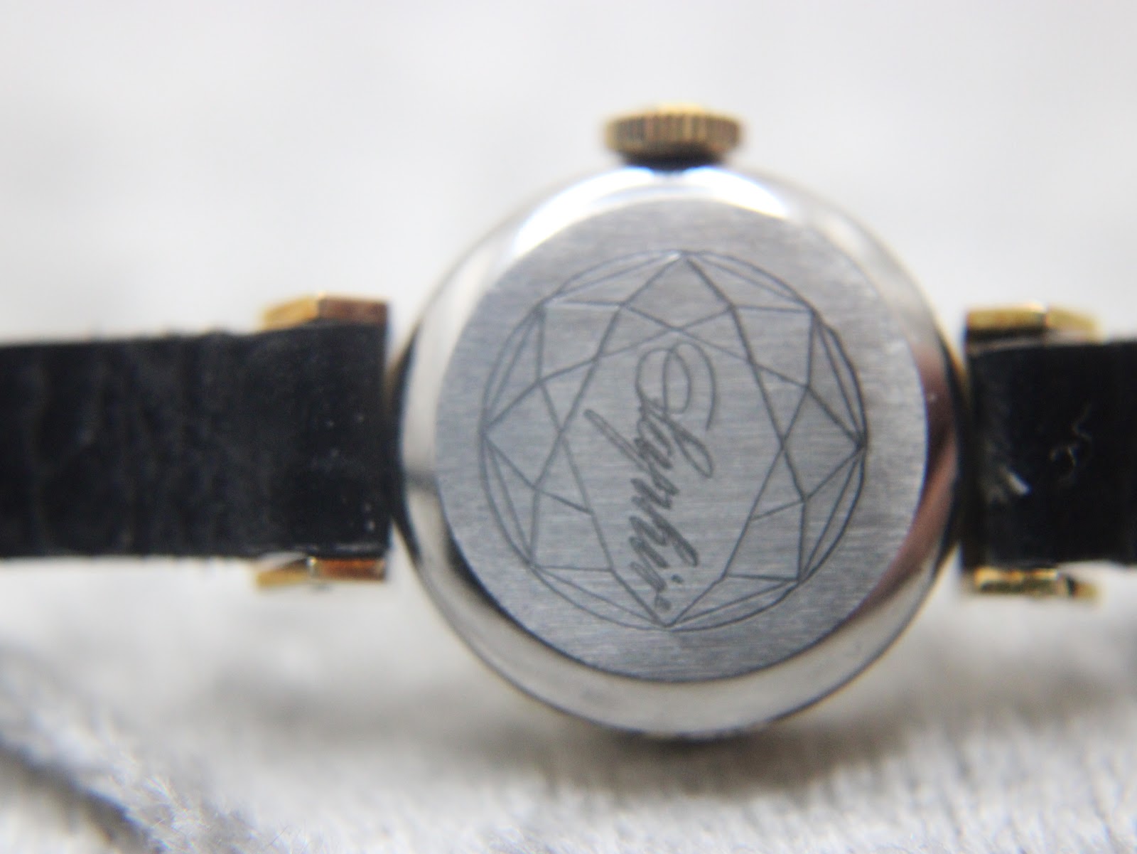 Close-up of the watch's stainless steel case back, engraved with a geometric pattern and "Ayphir" in script.