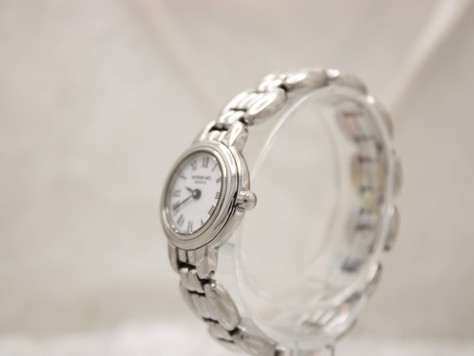 Angled side view of the Raymond Weil Genève 5880 watch on a display stand, highlighting the case profile and bracelet.