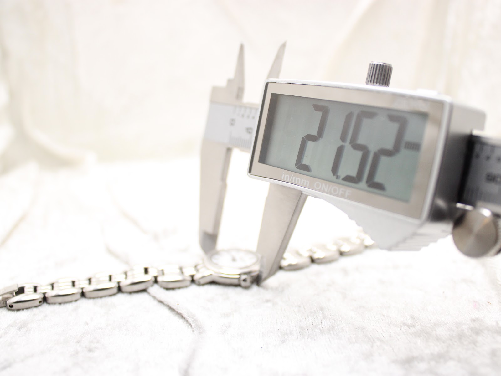 Close-up of a digital caliper accurately measuring the watch case diameter at 21.52mm.