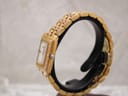 Side profile of the Raymond Weil Tango watch on a black display stand, highlighting the gold-tone case and crown.