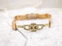 Detailed view of the open butterfly clasp on the gold-tone Raymond Weil bracelet, showing minor wear.