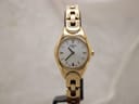 Front view of gold-tone Tissot G349 ladies watch with mother of pearl dial on a black watch stand.