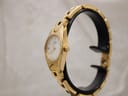 Side profile view of the gold-tone Tissot G349 watch on a stand, highlighting the case curvature and integrated bracelet.