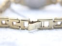 Close-up of the gold-tone folding clasp of the Tissot bracelet, with the 'T' logo engraved on its surface.
