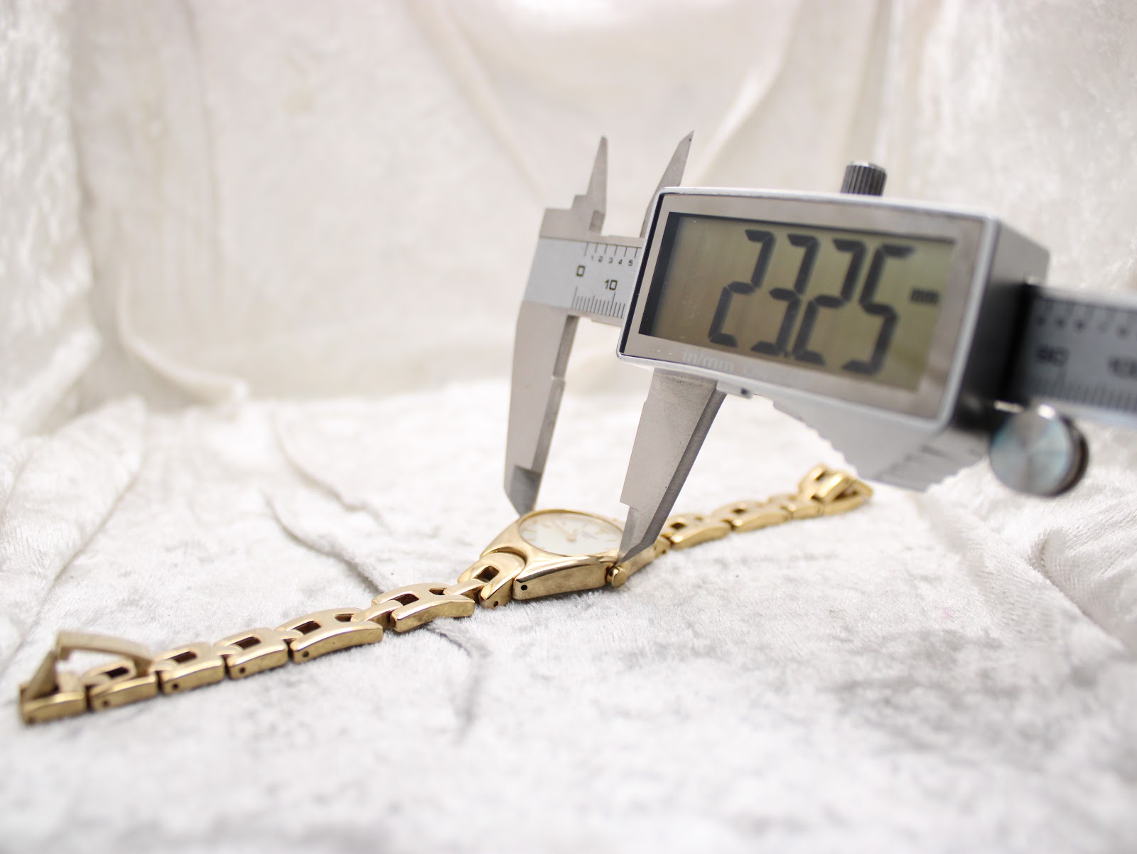 Digital caliper measuring the case diameter of the Tissot G349 watch, showing a precise reading of 23.25mm on the display.