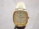 Front view of a Talis automatic gold-tone cushion case watch with champagne dial and baton indices, date at 3 o'clock.