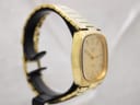 Left-side view of the gold-tone Talis watch, showing the cushion case profile and bracelet on a display stand.