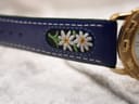 Close-up of the embroidered floral motif, likely an edelweiss, on the blue leather strap.