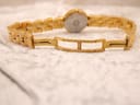 View of the watch back and extended bracelet with the folding clasp open, on a textured white surface.