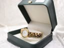 Watch placed inside an open dark green presentation box, showing the dial and gold-tone bracelet.