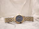 Full front view of the Raymond Weil Tango watch with its two-tone bracelet laid flat on a light textured surface.