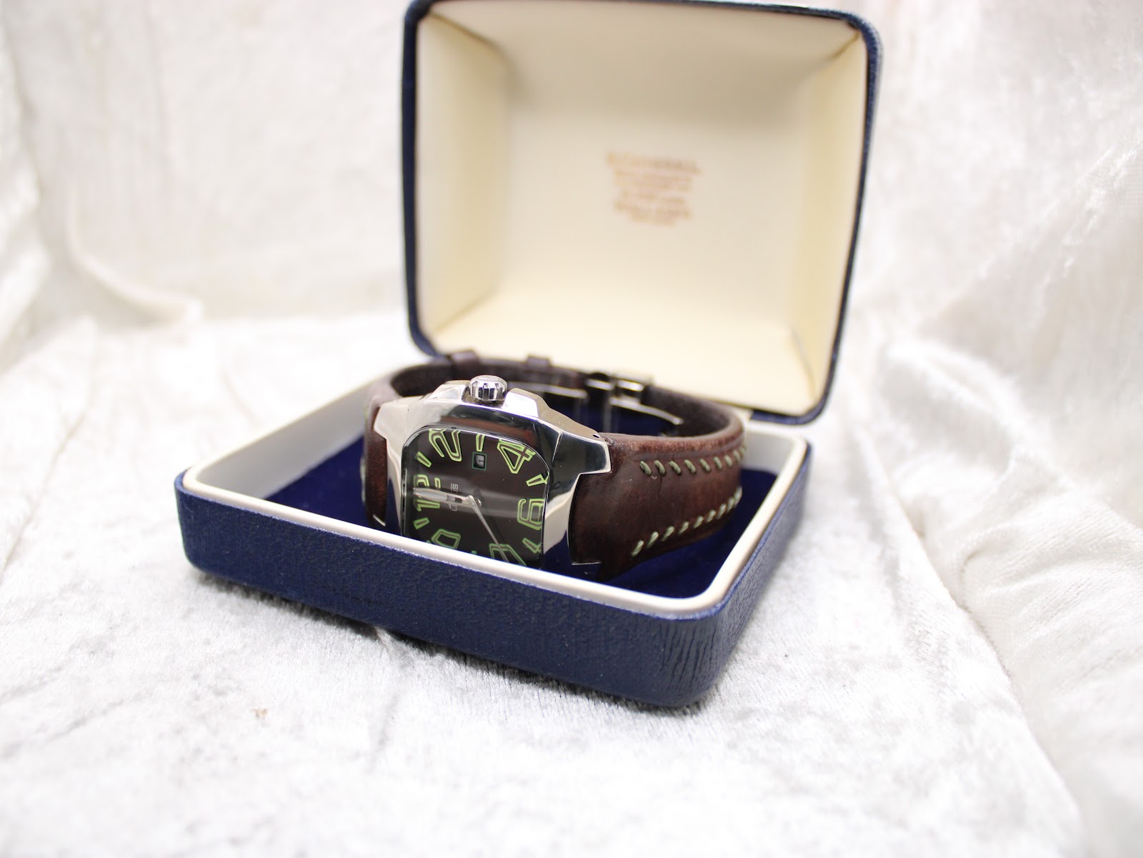 The Lotus 15509 watch resting inside a generic blue presentation box, positioned at an angle to display its dial and strap.