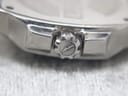 Extreme close-up of the watch crown, clearly showing the engraved Lotus logo on its textured surface.