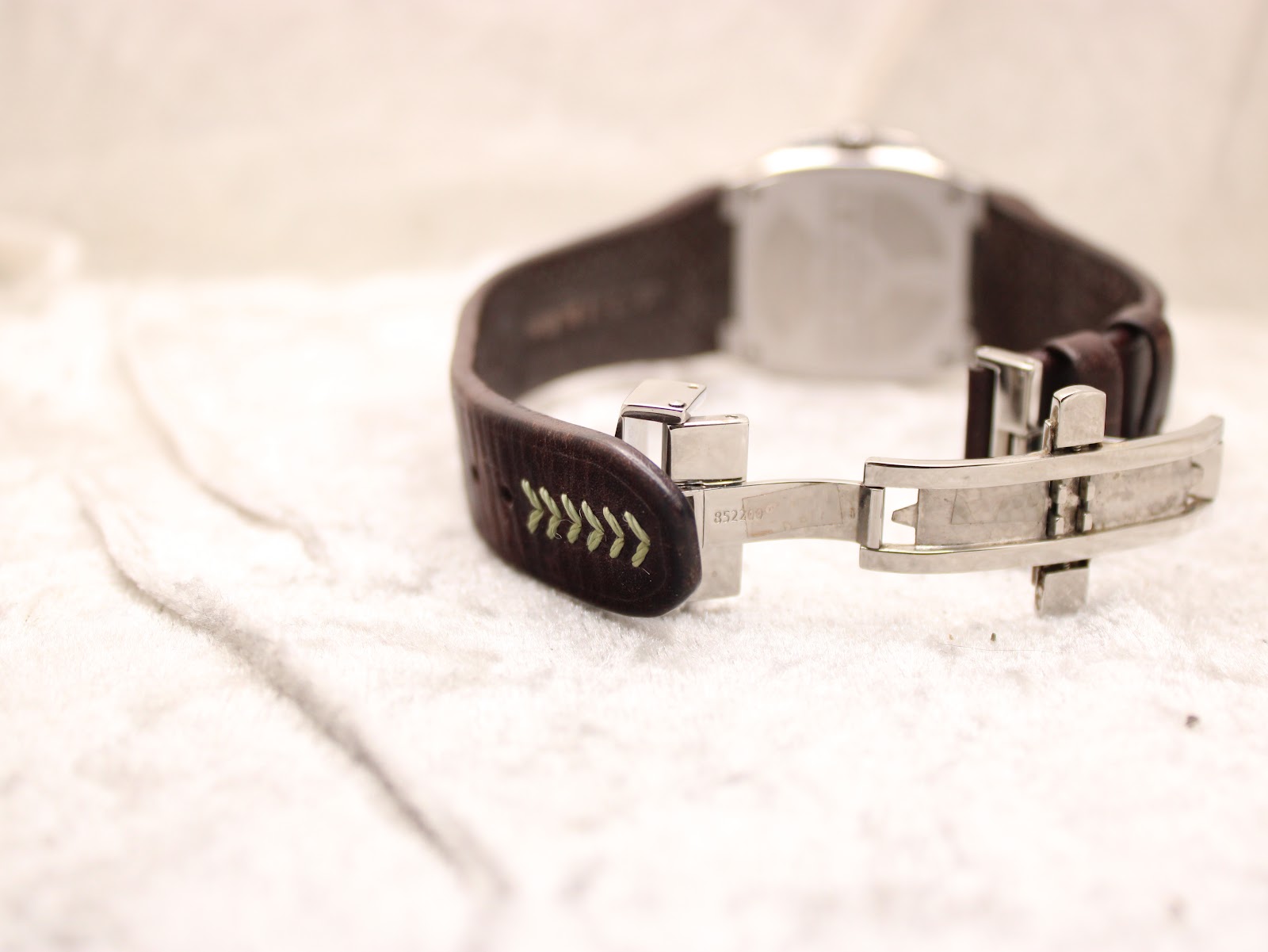 Rear view of the watch and strap, with the Lotus deployant clasp in an open position, revealing the strap holes and stitching details.