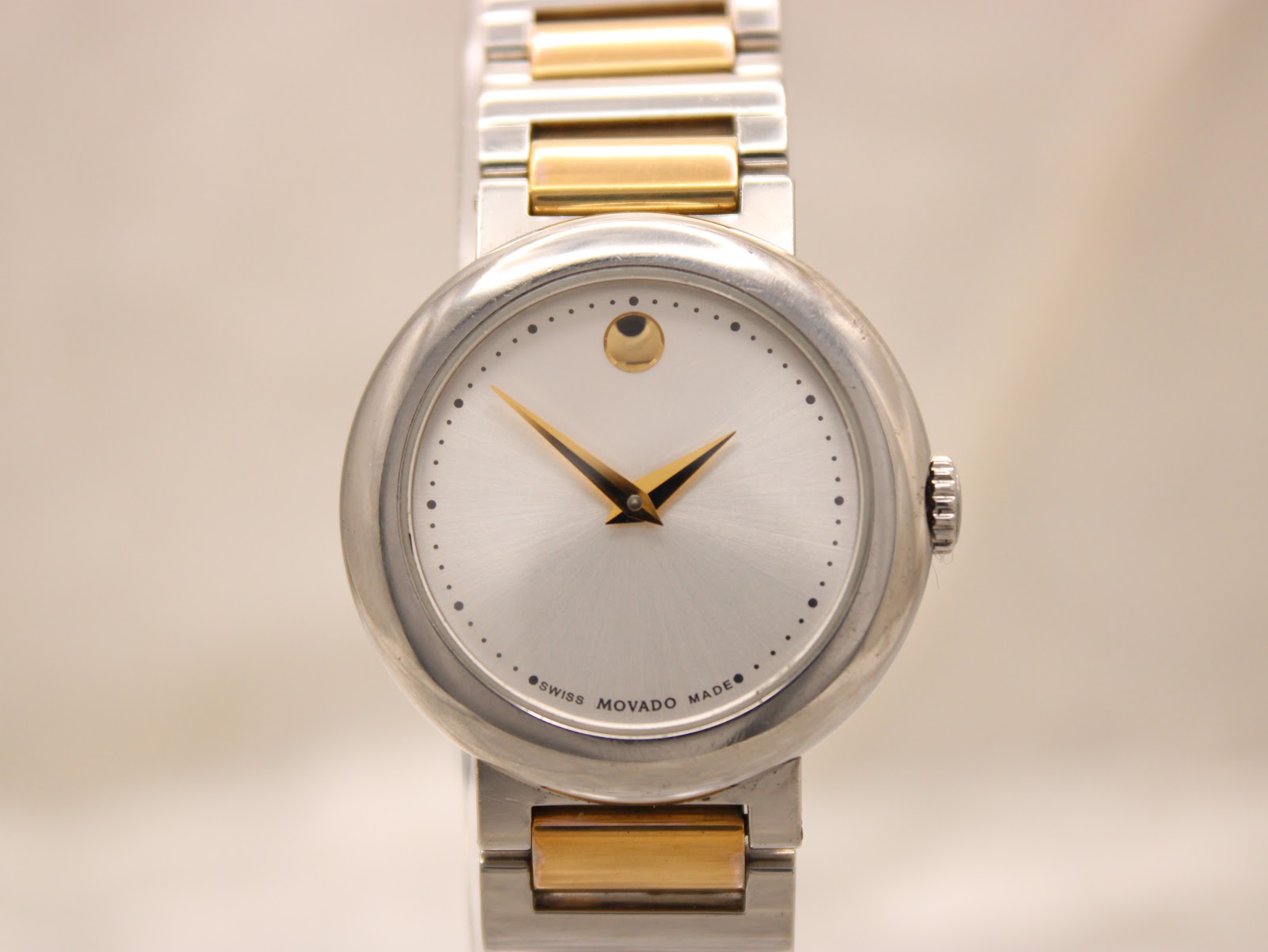 Close-up front view of the Movado Concerto dial, highlighting the silver sunburst finish, gold hands, and "SWISS MOVADO MADE" text.