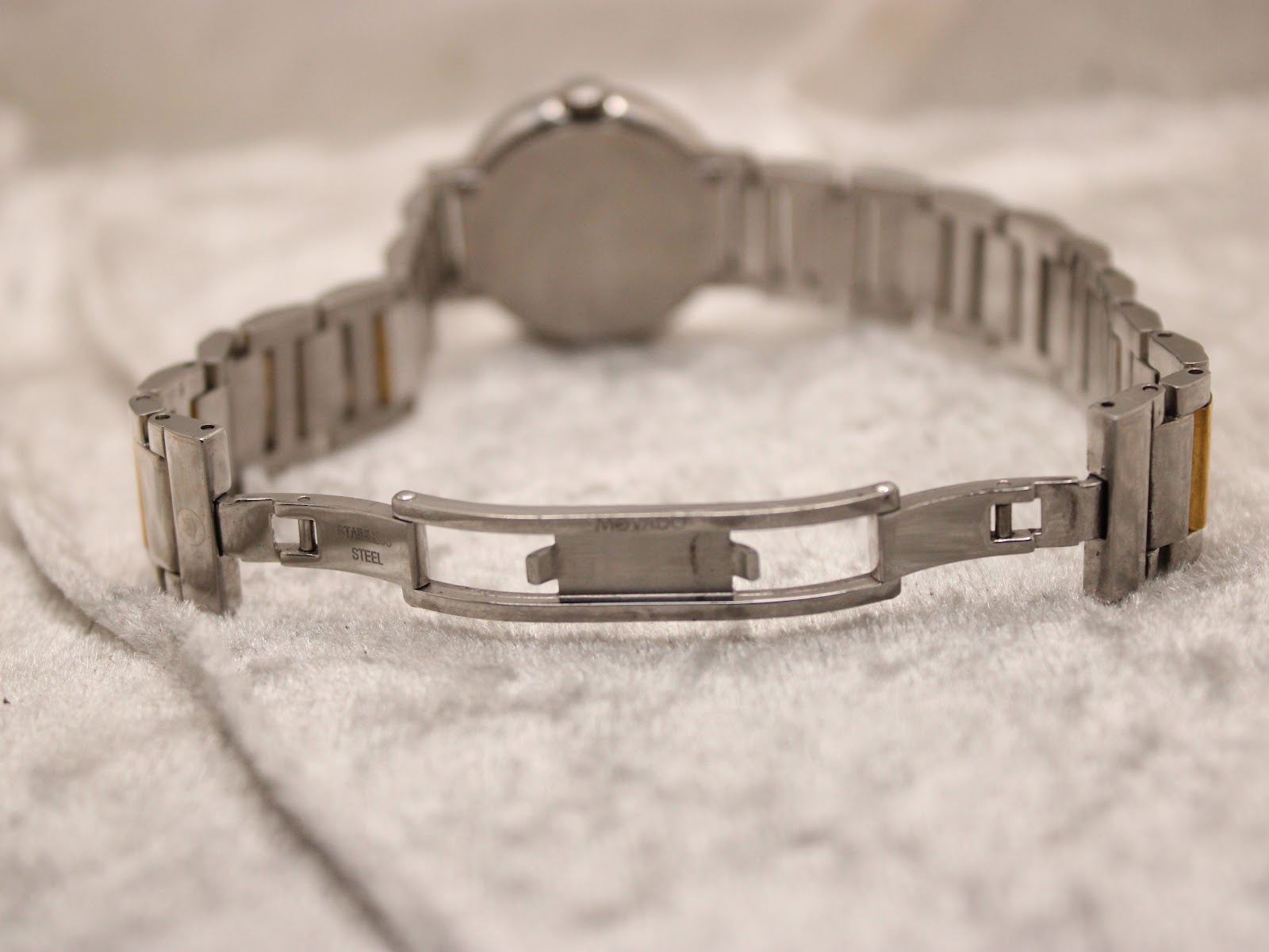 Detailed close-up of the Movado signed stainless steel fold-over clasp on the bracelet.