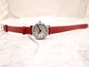Full top-down view of the Mondaine watch with the red leather strap fully extended, displaying the dial and strap from the front.