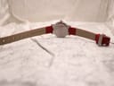 Another full back view of the Mondaine watch with the red leather strap fully extended, emphasising the strap's fastening holes and the details on the case back.