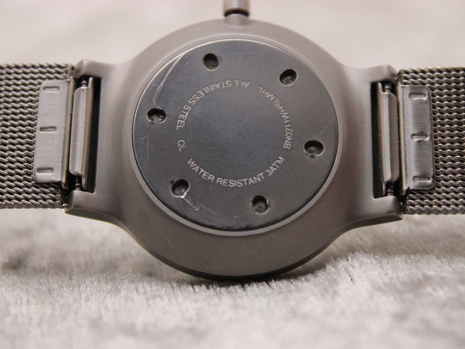 Close-up of the Braun BN0211 case back, showing 'ALL STAINLESS STEEL', 'BN0211WHSLMHL', and 'WATER RESISTANT 3ATM' engravings.
