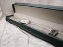 The Braun BN0211 watch with its silver mesh bracelet laid inside a dark green presentation box with a cream-coloured interior.